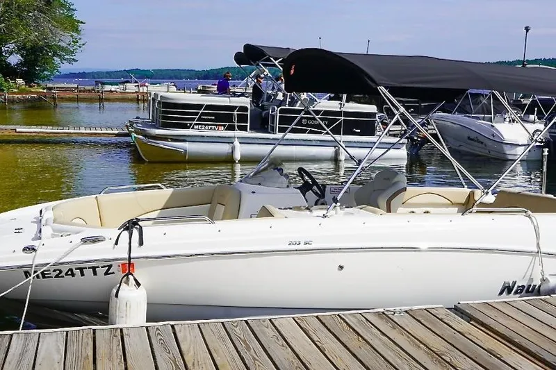 Slide: The Image of 2022 NauticStar 203 DC boat docked at a marina with other vessels. - 2