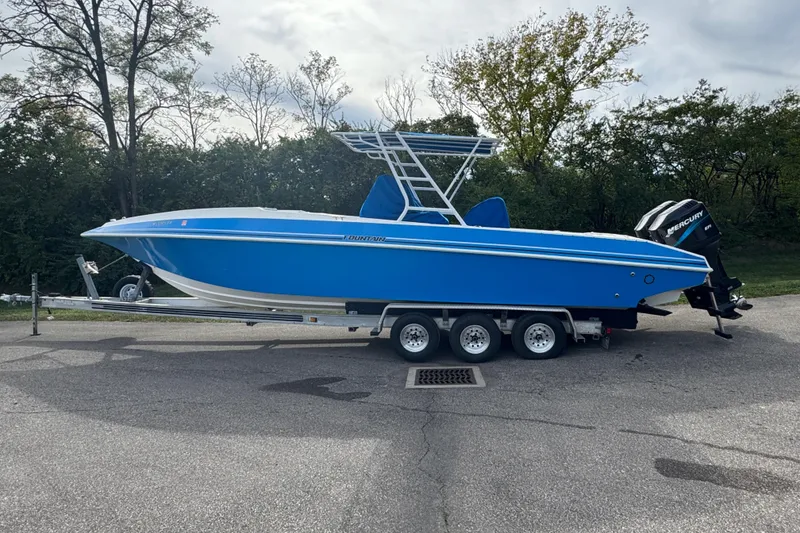 The Image of 2001 Fountain 31 Tournament Edition boat on trailer, blue hull, parked outdoors. - 1