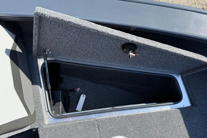 Slide: The Image of 2026 Lund 1875 Crossover XS boat storage compartment with open lid and interior view. - 12