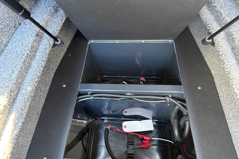 Slide: The Image of 2026 Lund 1875 Crossover XS boat storage compartment with wiring and battery setup. - 23