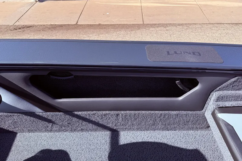 Slide: The Image of Interior view of 2026 Lund 1875 Crossover XS boat, showcasing storage compartment and branding. - 32