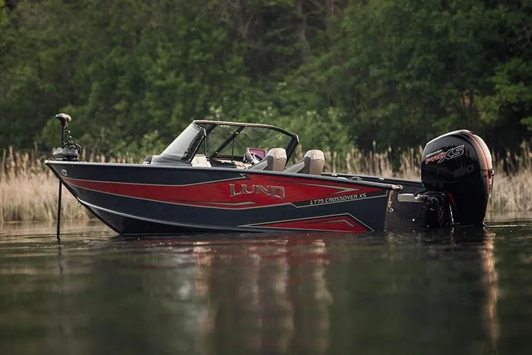 Slide: The Image of Manufacturer Provided Image: 2026 Lund 1875 Crossover XS boat on calm water, surrounded by lush greenery. - 4