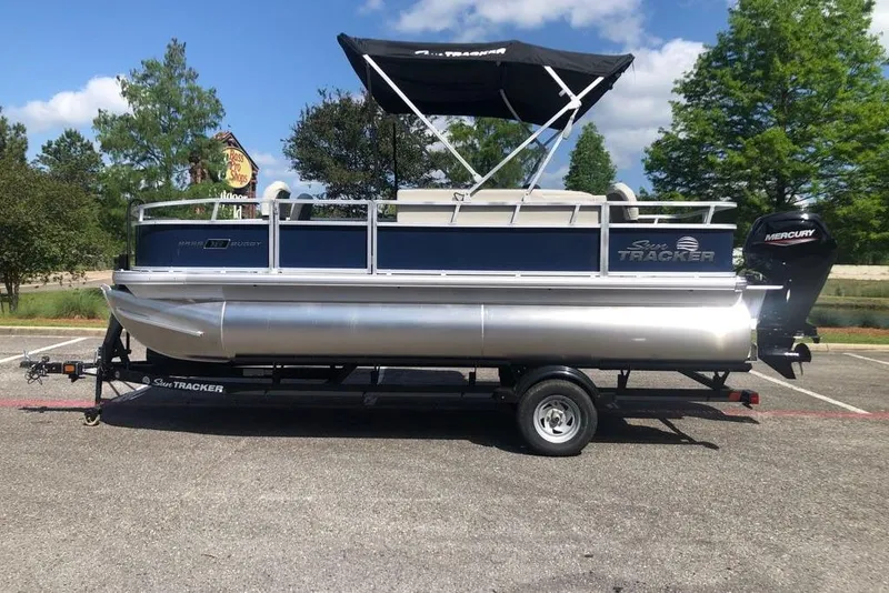The Image of 2026 Sun Tracker Bass Buggy 18 DLX pontoon boat on trailer, parked outdoors. - 0