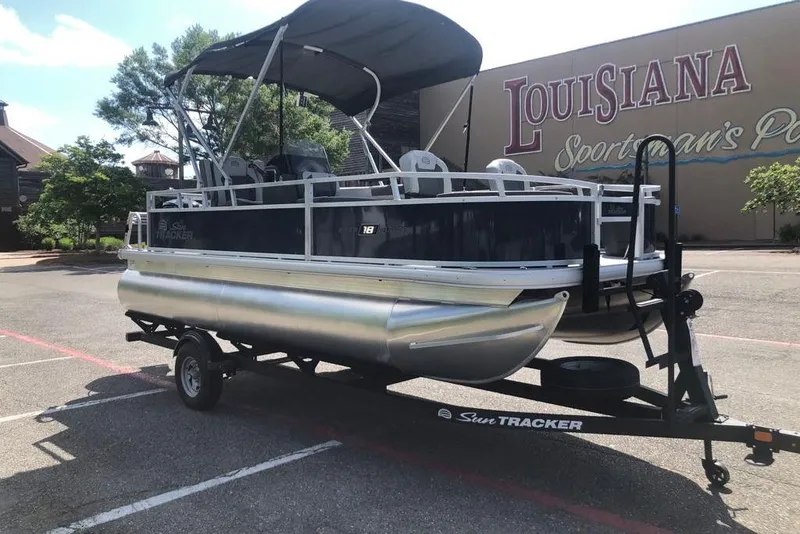 Slide: The Image of 2026 Sun Tracker Bass Buggy 18 DLX pontoon boat on trailer, parked outdoors. - 9