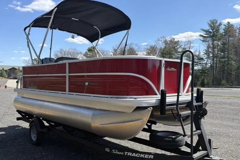 Slide: The Image of 2026 Sun Tracker Party Barge 18 DLX pontoon boat on trailer, red exterior, sunny day. - 1