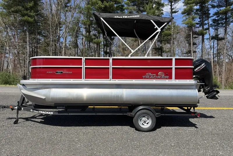 Slide: The Image of 2026 Sun Tracker Party Barge 18 DLX pontoon boat on trailer, parked outdoors. - 2
