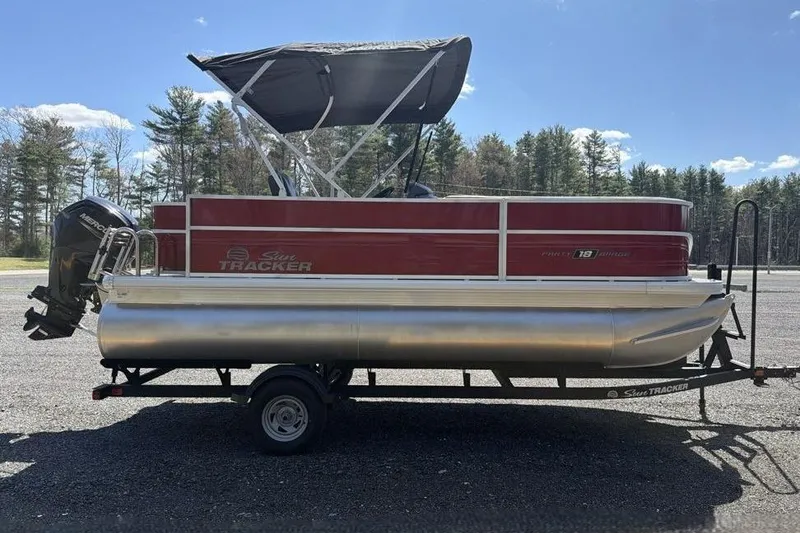 Slide: The Image of 2026 Sun Tracker Party Barge 18 DLX pontoon boat on trailer, parked outdoors. - 3