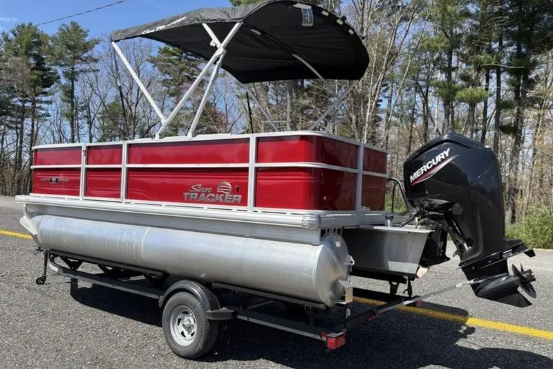 Slide: The Image of 2026 Sun Tracker Party Barge 18 DLX pontoon boat on trailer, with Mercury outboard motor. - 4