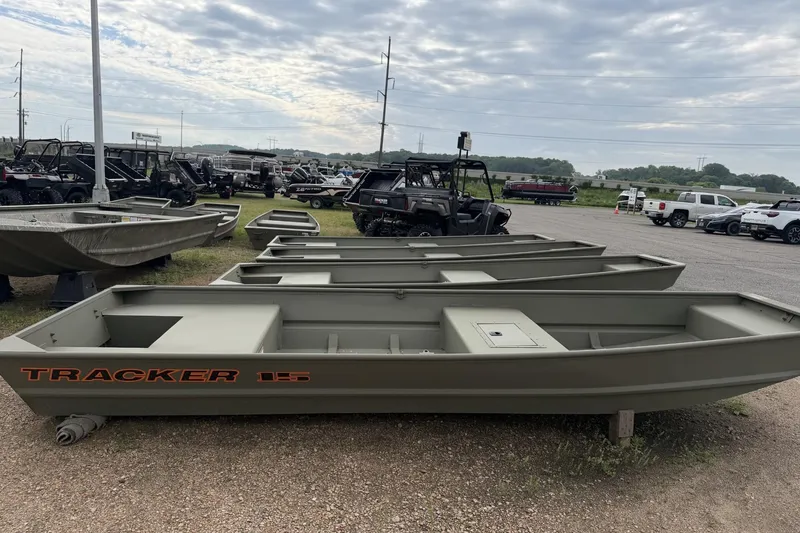The Image of 2026 Tracker Grizzly 15 Jon boat displayed outdoors with other vehicles. - 0