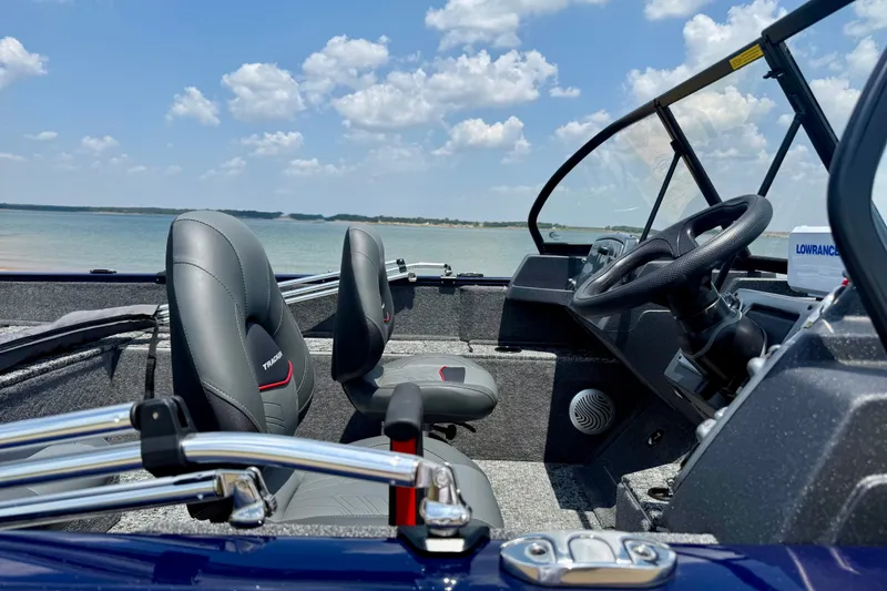 Slide: The Image of Interior of 2026 Tracker Pro Guide V-175 WT boat with steering wheel and seats, near water. - 3