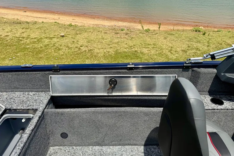 Slide: The Image of 2026 Tracker Pro Guide V-175 WT boat interior with seating and storage, near a lakeside. - 11