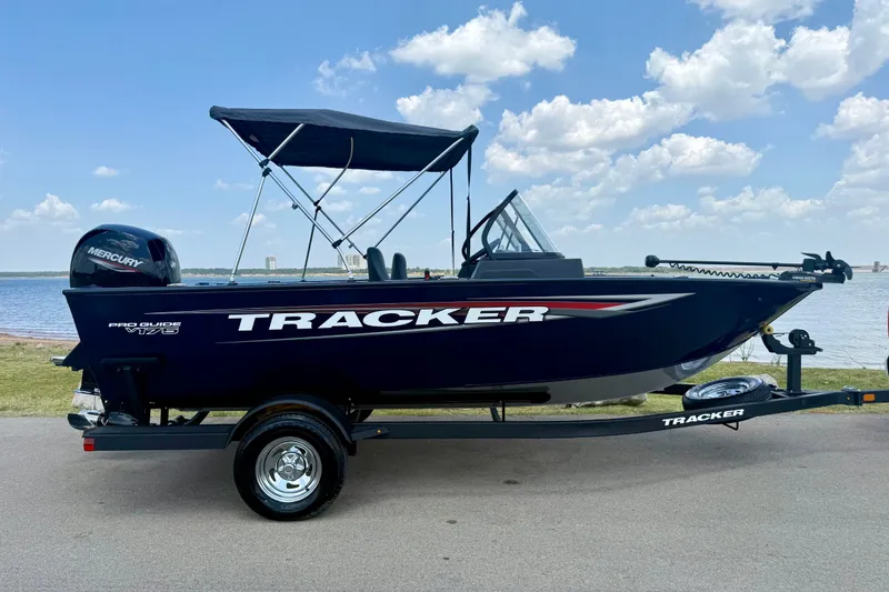 Slide: The Image of 2026 Tracker Pro Guide V-175 WT boat on trailer by a lake under blue sky. - 20