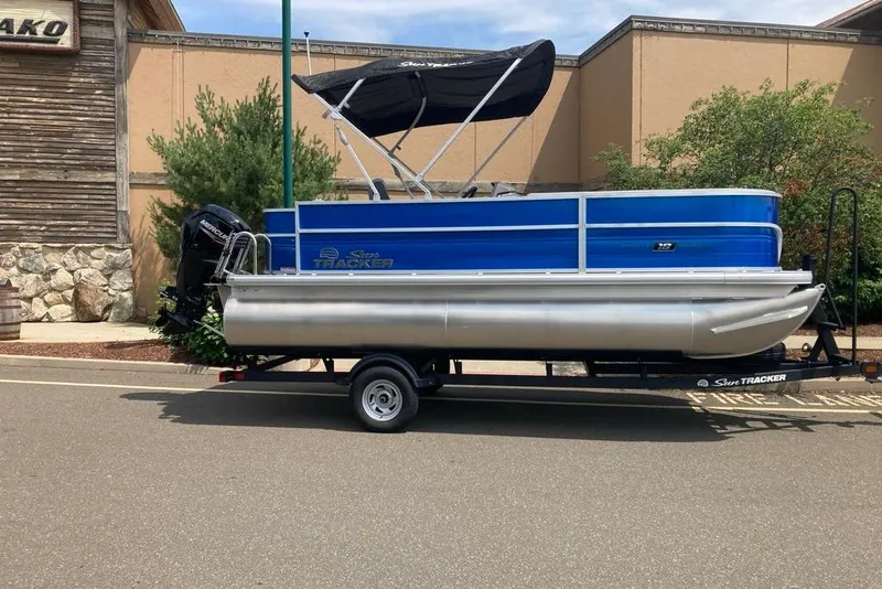 The Image of 2026 Sun Tracker Party Barge 18 DLX pontoon boat on trailer, parked outdoors. - 0