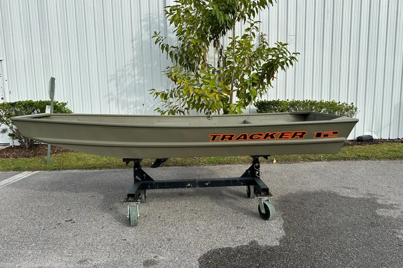 The Image of 2026 Tracker Grizzly 12 Jon boat on wheeled stand, outdoors near white building. - 0