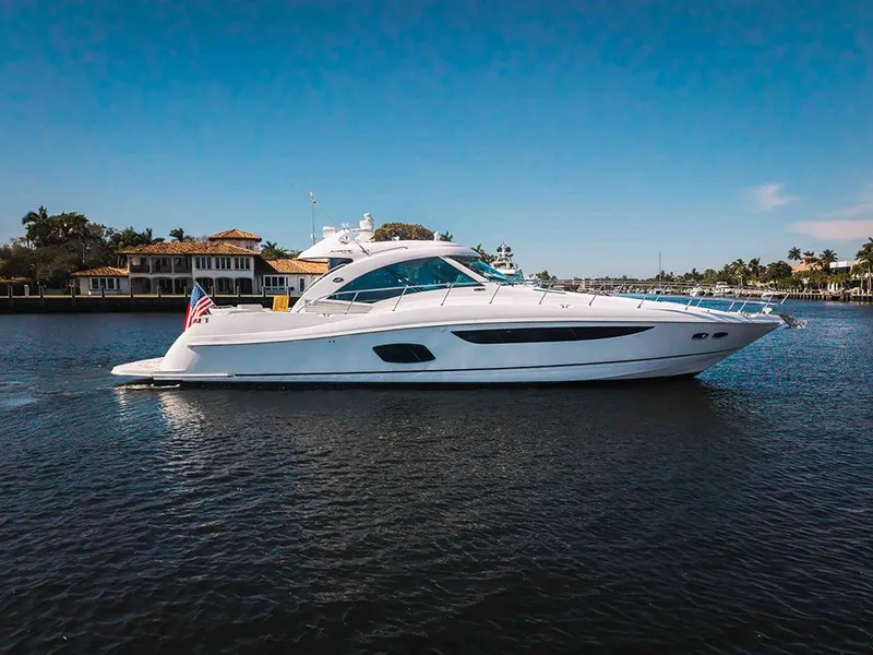 Slide: The Image of 2012 Sea Ray 610 Sundancer yacht cruising on a sunny day, near waterfront homes. - 2