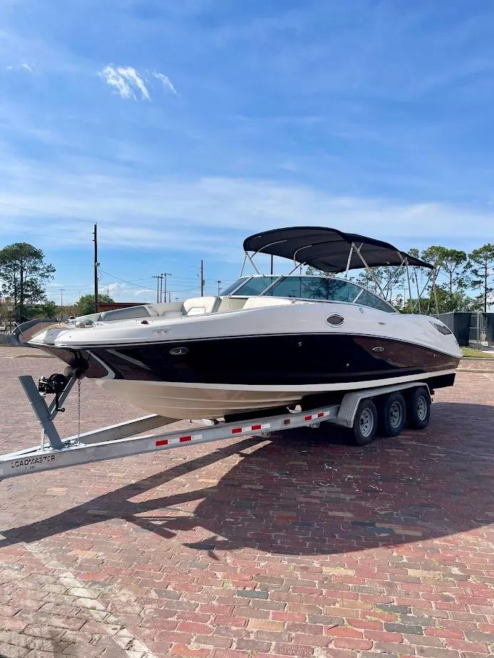 Slide: The Image of 2010 Sea Ray 300 Sundeck boat on trailer, parked outdoors under clear sky. - 6