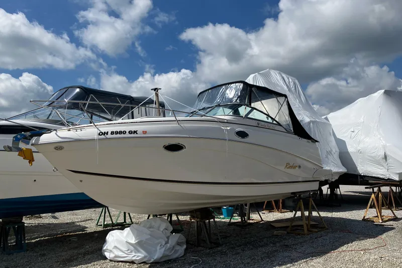 The Image of 2002 Rinker Fiesta Vee 250 boat on stands under a cloudy sky. - 1