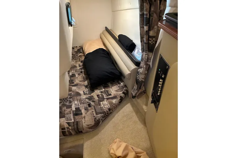 Slide: The Image of 2002 Rinker Fiesta Vee 250 cabin interior with patterned bedding and control panel. - 13