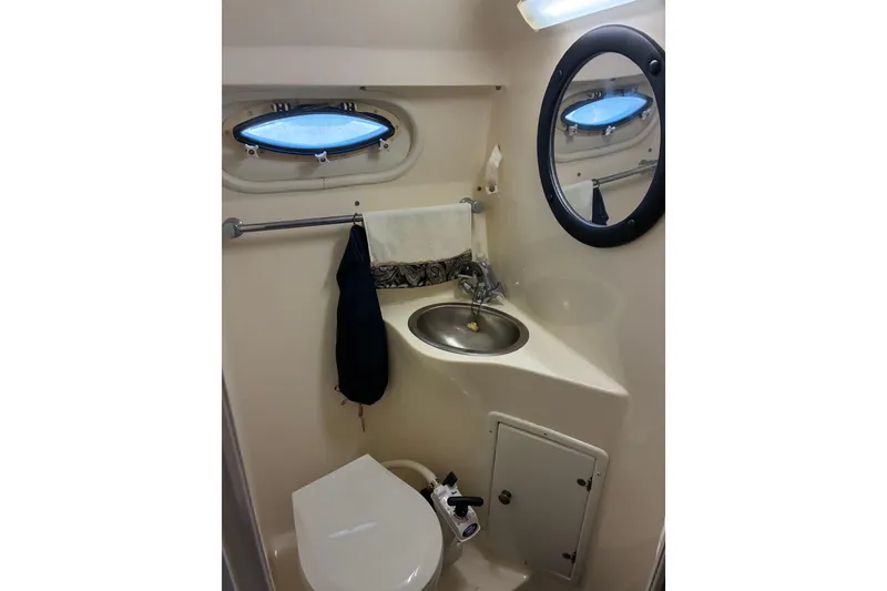 Slide: The Image of 2002 Rinker Fiesta Vee 250 boat bathroom with sink, toilet, and porthole window. - 17