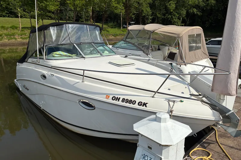 Slide: The Image of 2002 Rinker Fiesta Vee 250 boat docked in a marina, surrounded by trees. - 3