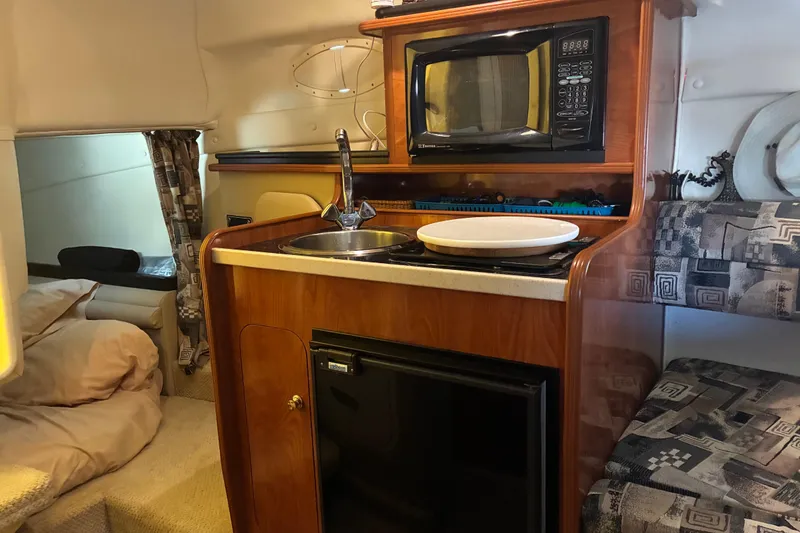 Slide: The Image of 2002 Rinker Fiesta Vee 250 cabin interior with kitchenette, microwave, and seating area. - 7