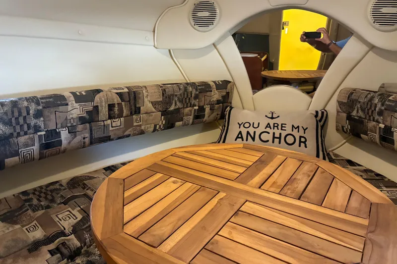 Slide: The Image of Interior of 2002 Rinker Fiesta Vee 250 with wooden table and nautical-themed pillow. - 9