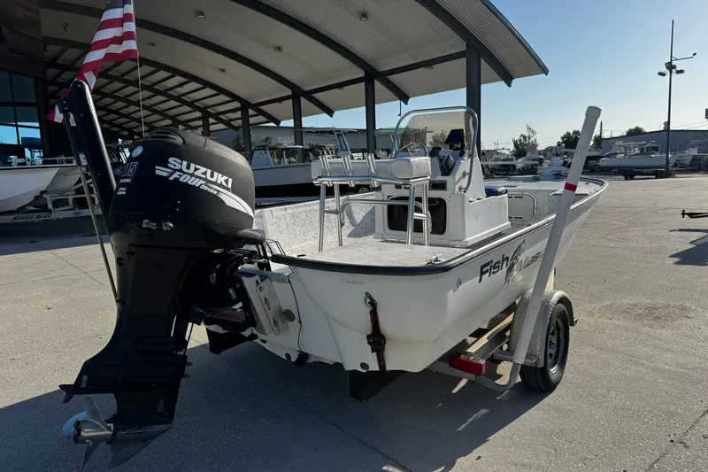 Slide: The Image of 2002 Fishmaster 19 boat with Suzuki outboard motor on trailer, parked outdoors. - 3