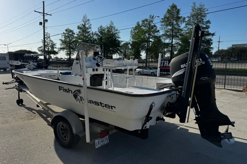 Slide: The Image of 2002 Fishmaster 19 boat on trailer with Suzuki outboard motor, parked outdoors. - 5