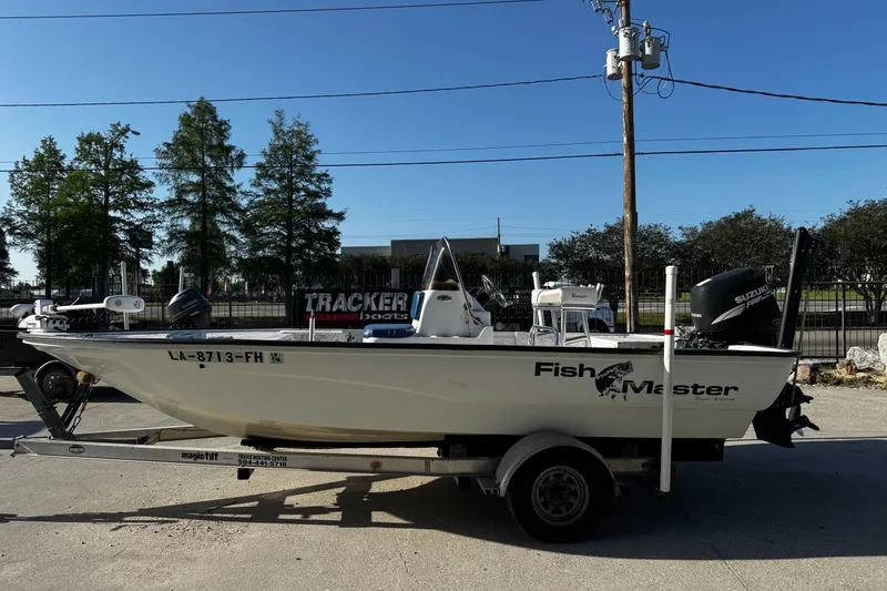 Slide: The Image of 2002 Fishmaster 19 boat on trailer with Suzuki outboard motor, parked outdoors. - 6
