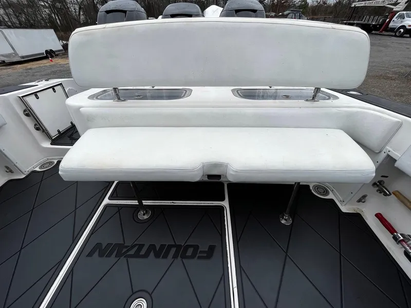 Slide: The Image of 2011 Fountain 38 CC Tournament Edition boat interior with white seating and storage compartments. - 27