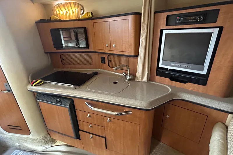 Slide: The Image of 2006 Sea Ray 300 Sundancer cabin kitchen with wood cabinetry, sink, and built-in appliances. - 11