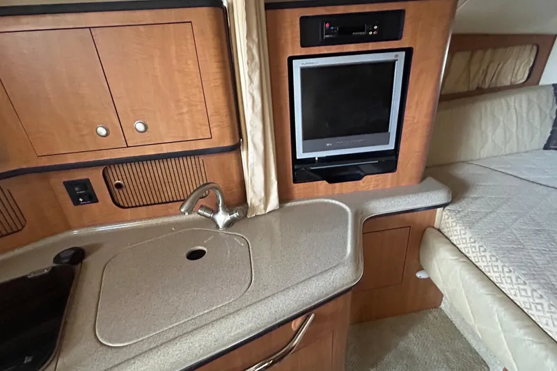 Slide: The Image of 2006 Sea Ray 300 Sundancer interior with kitchenette, sink, and TV. - 17