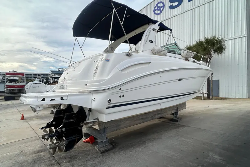 Slide: The Image of 2006 Sea Ray 300 Sundancer boat on dry dock with canopy and dual propellers. - 2