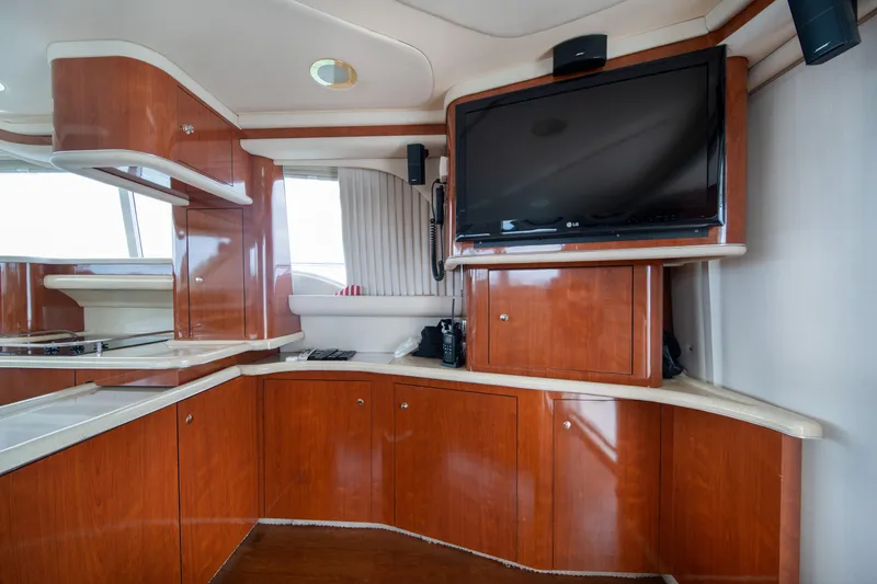 Slide: The Image of Interior of 2003 Sea Ray 480 Sedan Bridge with wood cabinetry and mounted TV. - 21