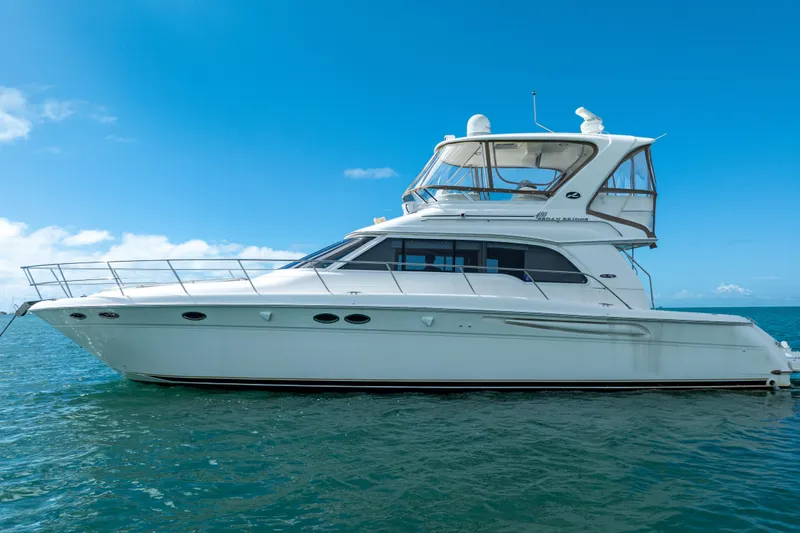 Slide: The Image of 2003 Sea Ray 480 Sedan Bridge yacht on calm blue waters under clear sky. - 7
