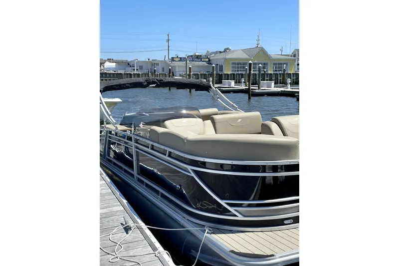 Slide: The Image of 2022 Starcraft CX 23 Q pontoon boat docked at marina under clear blue sky. - 11
