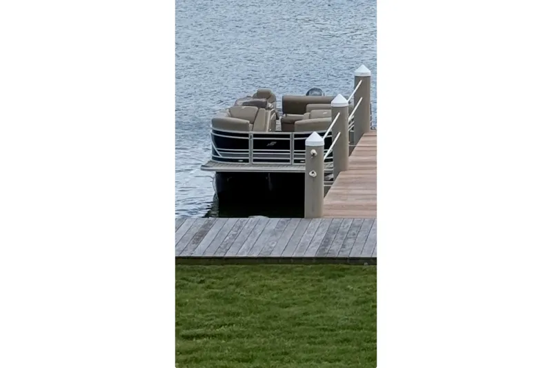 Slide: The Image of 2022 Starcraft CX 23 Q pontoon boat docked on a serene lake. - 13