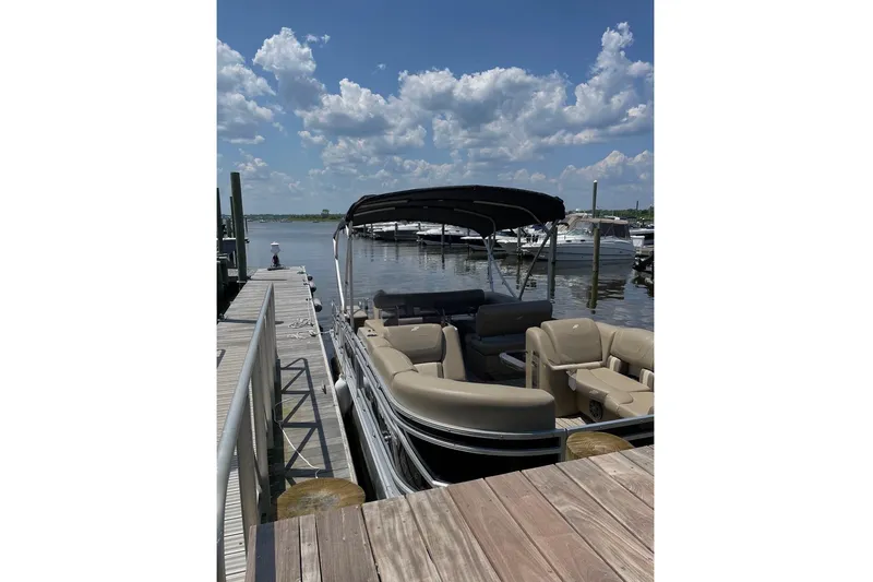 Slide: The Image of 2022 Starcraft CX 23 Q pontoon boat docked at marina under a partly cloudy sky. - 14