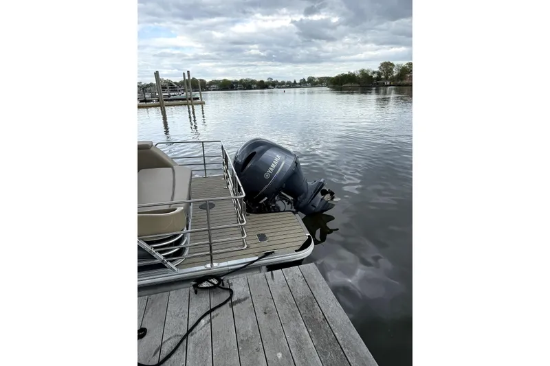 Slide: The Image of 2022 Starcraft CX 23 Q pontoon boat docked with Yamaha outboard motor on a calm lake. - 15
