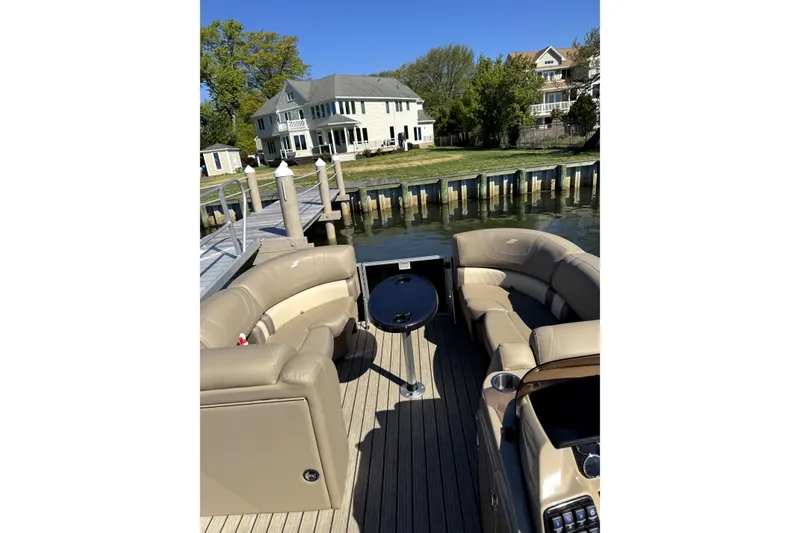 Slide: The Image of 2022 Starcraft CX 23 Q pontoon boat with beige seating, docked near waterfront homes. - 17