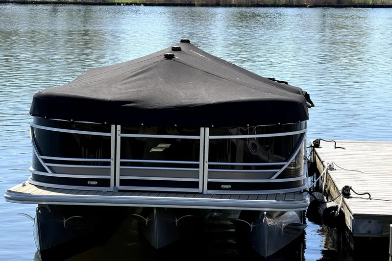 Slide: The Image of 2022 Starcraft CX 23 Q pontoon boat docked with black cover on water. - 18