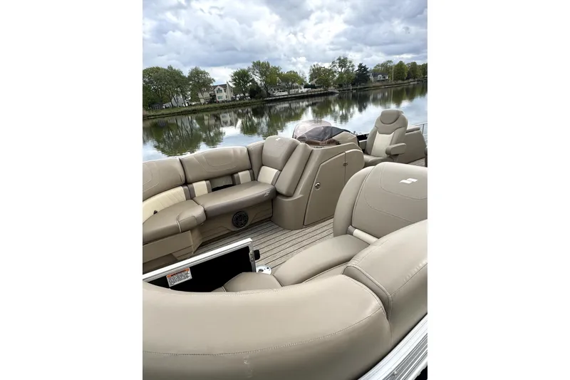 Slide: The Image of 2022 Starcraft CX 23 Q pontoon boat with beige seating, docked on a calm lake. - 19
