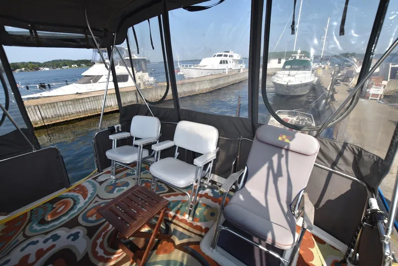 Slide: The Image of 1985 Silverton 40 Aft Cabin interior with chairs, table, and colorful rug, docked by the water. - 13