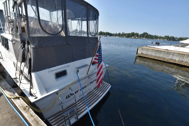 Slide: The Image of 1985 Silverton 40 Aft Cabin yacht docked with American flag, calm waters. - 2
