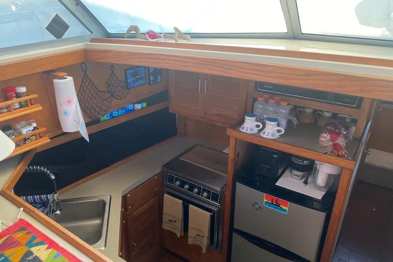 Slide: The Image of 1985 Silverton 40 Aft Cabin kitchen with sink, stove, and storage shelves. - 23