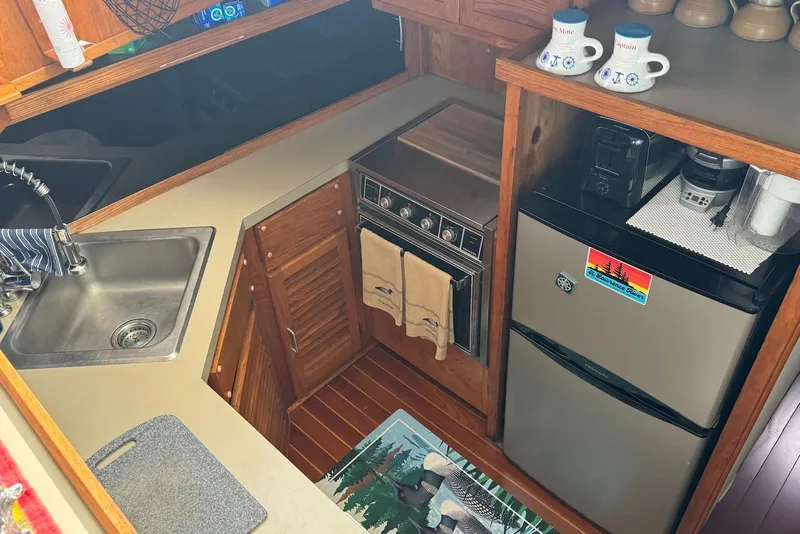 Slide: The Image of 1985 Silverton 40 Aft Cabin kitchen with sink, stove, fridge, and countertop appliances. - 26