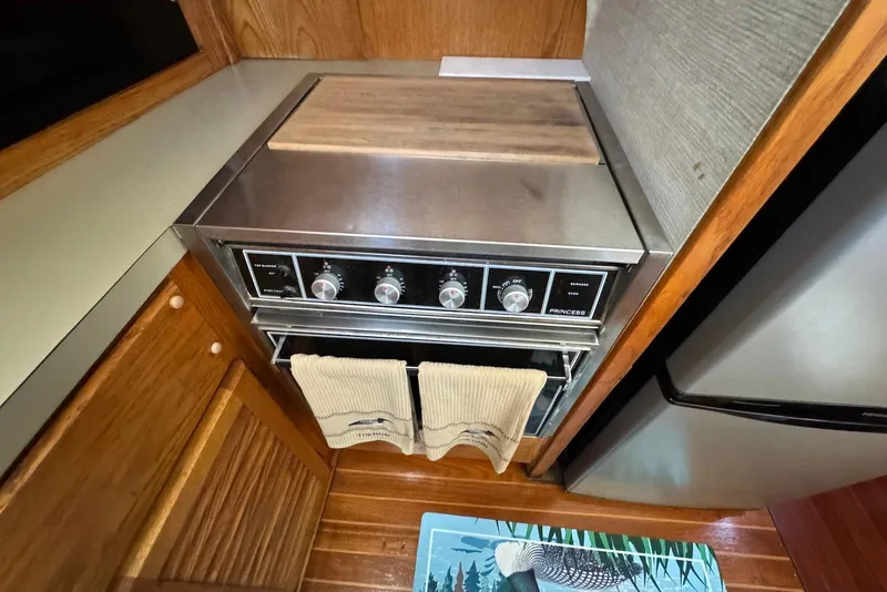 Slide: The Image of 1985 Silverton 40 Aft Cabin kitchen with stainless steel stove and wooden cabinetry. - 27