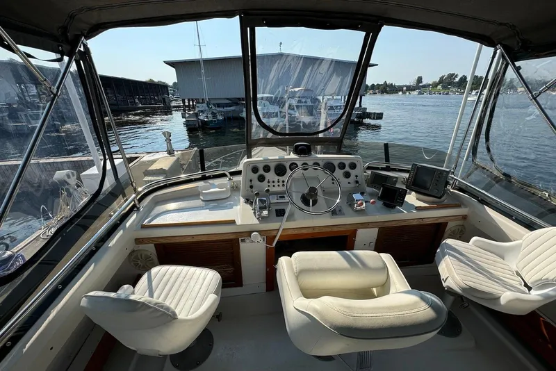 Slide: The Image of 1985 Silverton 40 Aft Cabin helm with steering wheel, gauges, and marina view. - 3