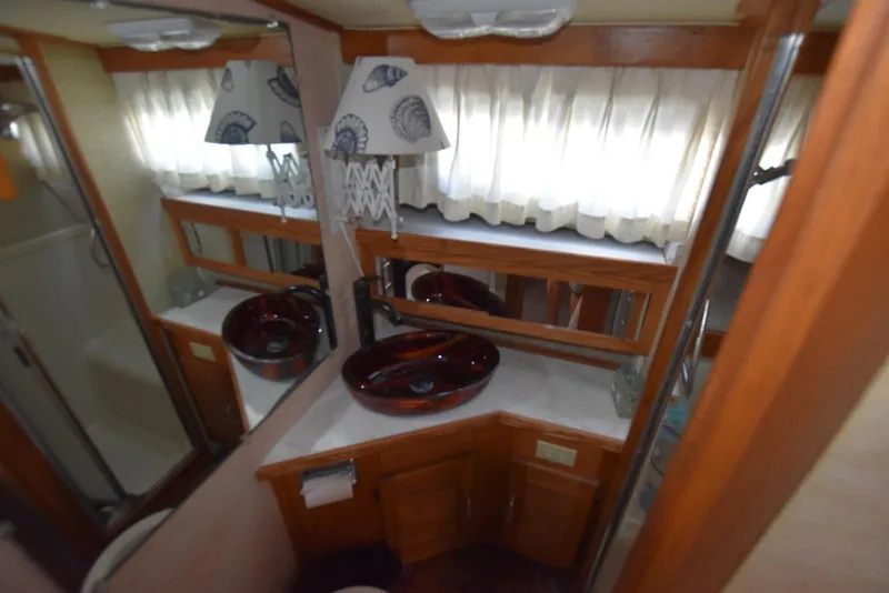 Slide: The Image of 1985 Silverton 40 Aft Cabin bathroom with modern sink, wooden cabinetry, and nautical decor. - 33