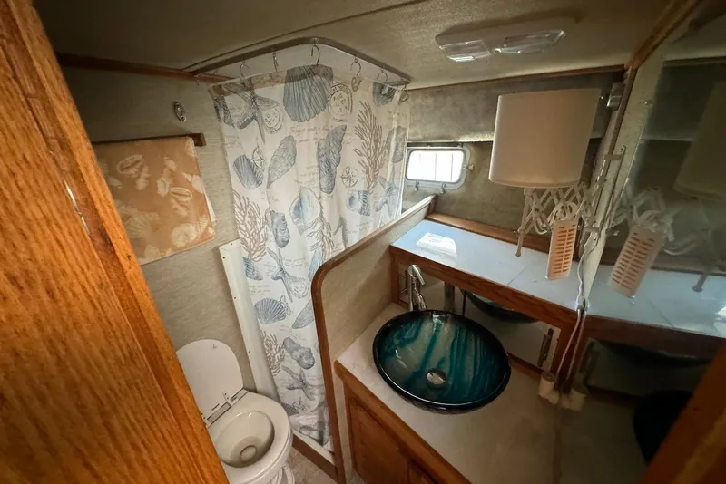 Slide: The Image of 1985 Silverton 40 Aft Cabin bathroom with nautical decor, vessel sink, and shower curtain. - 41